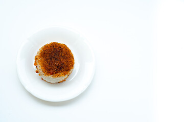 A single serving of Indonesian sticky rice, or ketan serundeng, with a toasted coconut topping on a white plate, isolated on a white background.