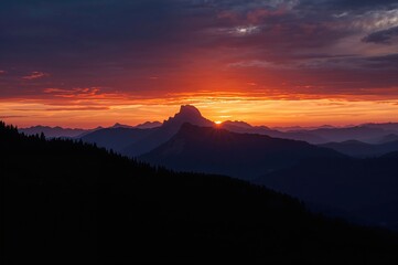 Dusk silhouettes of mountain landscape with the sun setting behind peaks