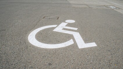Handicap parking space indicator painted on pavement for wheelchair users in an open area with no vehicles or pedestrians on a gray concrete surface