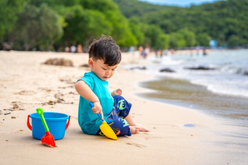 Asian boy playing on the sandy beach by the sea
