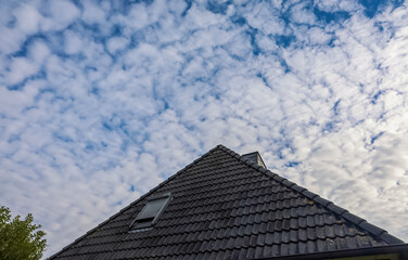 Fototapeta premium Roof of a house under cloudy blue sky