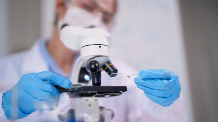 Scientist researcher using microscope in laboratory examining biology sample plant tissue for medical discovery and academic research