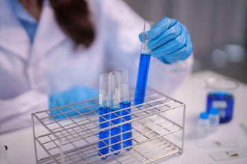 Scientist adult performs chemical analysis laboratory research test tubes blue liquid solution development science professional experiment investigation innovation discovery