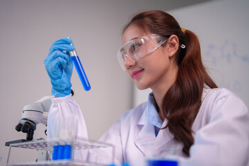 Asian female scientist adult conducting laboratory research examining test tube scientific discovery in modern science lab