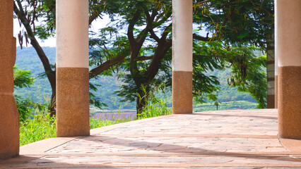 Curve walkway and row of stone columns with many green trees and beautiful natural view in viewpoint area on the hill, exterior architecture decoration in vintage design