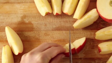 Hand is chopping apple slices on wooden cutting board. Top view. - Powered by Adobe