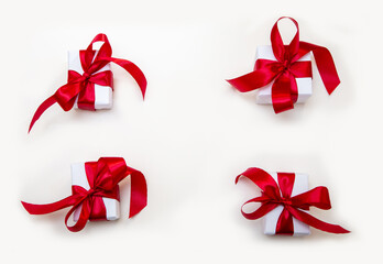 White gift boxes with red satin ribbons on a white background. Festive composition for Christmas, New Year, and Valentines Day.
