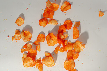 Scattered orange cassava chips on white surface showing crispy texture and natural shadows.