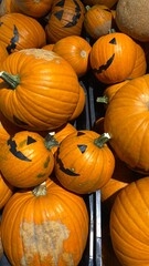 Smiling Halloween pumpkins with black faces on orange background