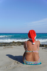 Mature woman wearing Santa hat on tropical beach