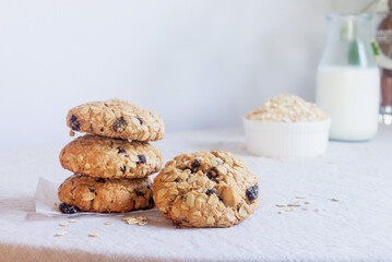 A freshly baked oatmeal raisin cookie with visible oats placed on natural linen tablecloth background.