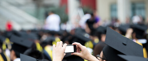 graduates taking photos by cellphone during commencement.