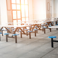 Clean school cafeteria with many empty seats and tables.