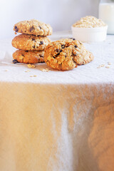 A freshly baked oatmeal raisin cookie with visible oats placed on natural linen tablecloth background.