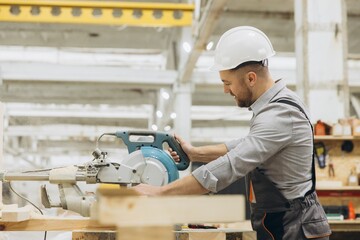 Carpenter cutting wooden plank with circular saw in workshop