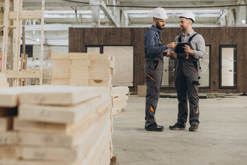 Construction workers using digital tablet in modular building factory