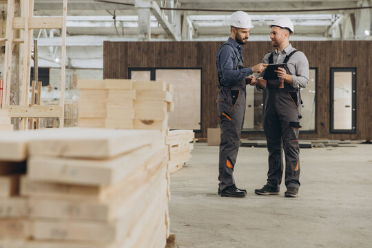 Construction workers using digital tablet in modular building factory