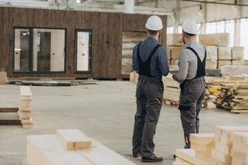 Construction workers inspecting modular building in factory
