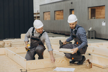 Carpenters building wooden frame in workshop for modular house