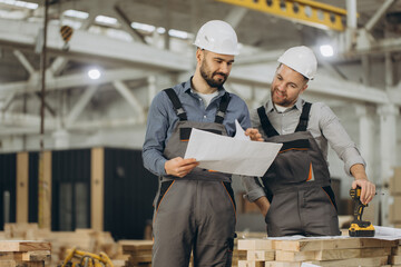 Construction engineers reviewing building plans in workshop
