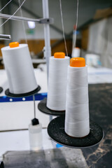 Reels of textile yarn thread at industrial sewing machine