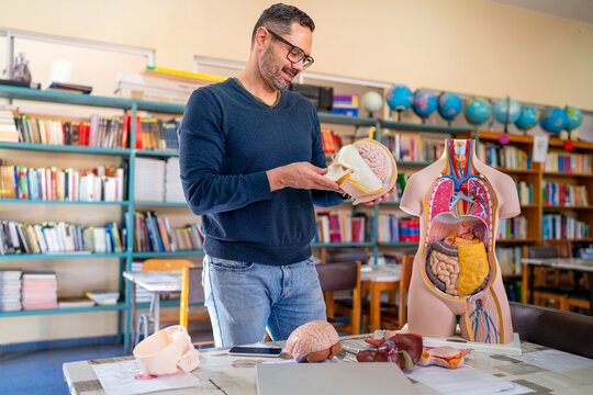 Experienced teacher explaining human anatomy using models in a classroom setting - Powered by Adobe