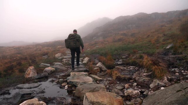 A man hiking up a foggy mountain trail