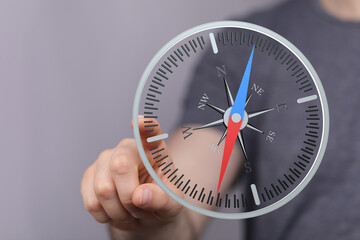 Close-up of hand holding a compass. The compass shows direction and navigation. Concept of choices, options, and finding the right path