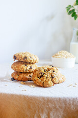A freshly baked oatmeal raisin cookie with visible oats placed on natural linen tablecloth background.