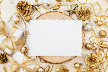 Handmade cotton paper card on wooden slice with golden Christmas and New Year decorations. Elegant flat lay with copy space for text or design.