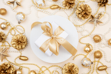 Golden Christmas and New Year frame with gifts, ornaments, pine cones, and pearls. Flat lay background with copy space for text or festive design.