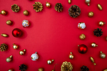 Red background with golden and red baubles and pinecones. Minimal festive composition with copy space, perfect for advertising or greeting cards.