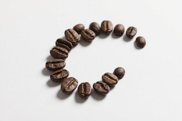 A curved upward arc composed of multiple deep brown coffee beans of varying sizes, arranged in an orderly yet natural pattern against a clean white background, highlighting texture and three-dimension