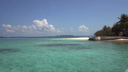 Luxury resort photo of Maldives tropical paradise island in Indian Ocean with palm trees. Beautiful photography, breakwater, 
coral reef, azure ocean, sky with clouds on horizon.