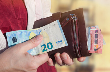 Leather wallet and euro banknotes in a woman's hands, selective focus.	