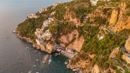 Atardecer en la costa de Amalfi, Italia, con casas sobre acantilados y barcos en el mar