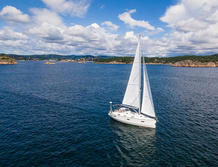 Fototapeta premium Sailboat cruising along the Norwegian coastline on a sunny summer day