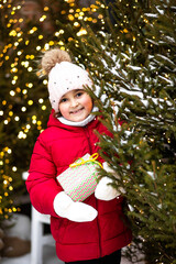 Cute little girl standing nearby Christmas tree snowy winter outside