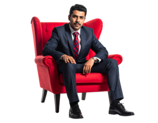 Confident man in a navy suit sits relaxed in a red armchair against a black background