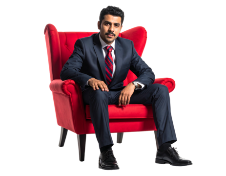 Confident man in a navy suit sits relaxed in a red armchair against a black background