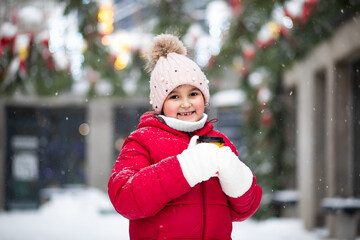 Happy child girl holding mug of hot cocoa, chocolate or tea. Children activity in winter day. Holiday vacation concept.