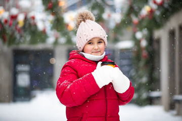 Happy child girl holding mug of hot cocoa, chocolate or tea. Children activity in winter day. Holiday vacation concept.