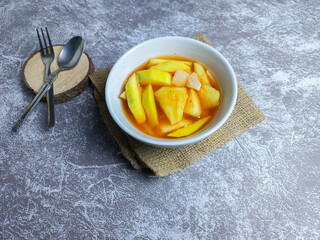 Asinan buah or pickled fruit in a bowl on a gray background. fresh Indonesian dessert spicy, sweet, and sour taste 