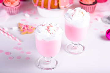 Pink Christmas milkshake. Traditional fruit cake and cupcakes on the background. Winter festive table. Holiday celebrate concept.