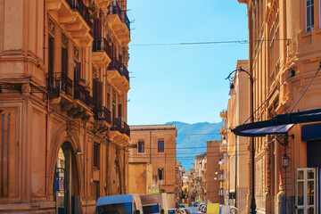 Picturesque street in Palermo, Italy, with historic buildings featuring ornate balconies and architectural details. Street with mountains in the background  highlighting blend of urban beauty © Leilani