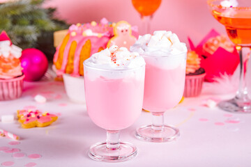 Pink Christmas milkshake. Traditional fruit cake and cupcakes on the background. Winter festive table. Holiday celebrate concept.