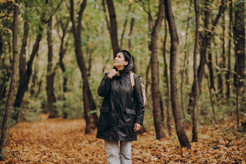 Woman with backpack hiking on footpath in autumn forest and relaxing outdoor.