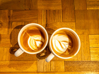 Hot latte, coffee with milk, and foam art on top in white ceramic cup on wooden table, in warm mood