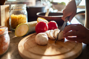 Adult slicing mushrooms in kitchen