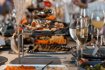 Luxurious Fine Dining Setup: Multi-Tiered Appetizer Stand with Smoked Salmon, Figs, Champagne, and Elegant Table Setting, Warm Tones.